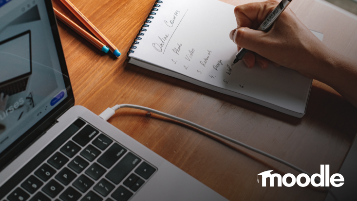 Person schreibt in Notizblock neben Laptop