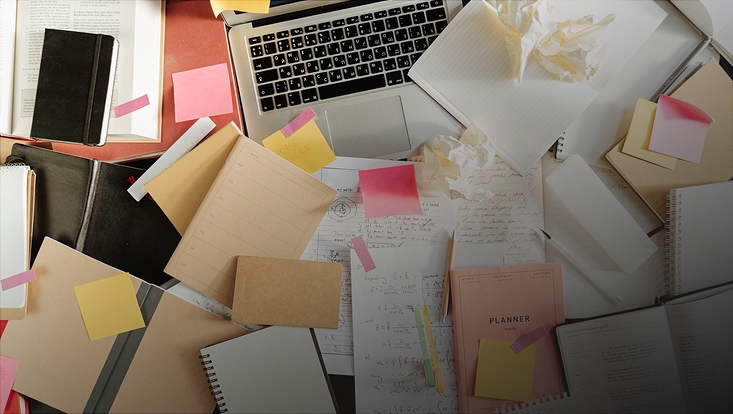 Laptop auf Schreibtisch bedeckt von Papiere