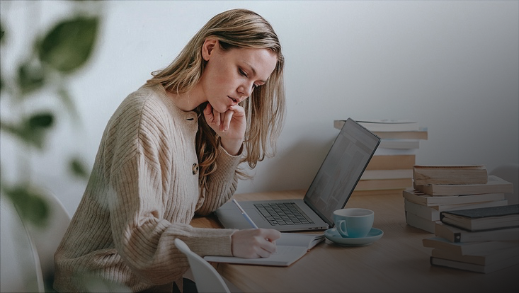 Frau vor Laptop macht Notizen