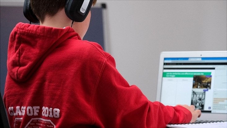 Junger Schüler mit Kopfhörer vor dem Computer