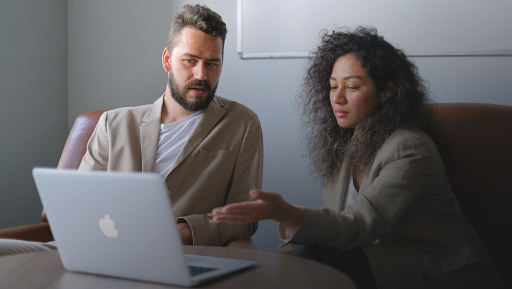 Mann und Frau diskutieren vor Laptop