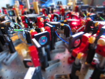 >Optischer Aufbau, in dem Laserstrahlen vorbereitet werden, um damit die Atome zu kühlen